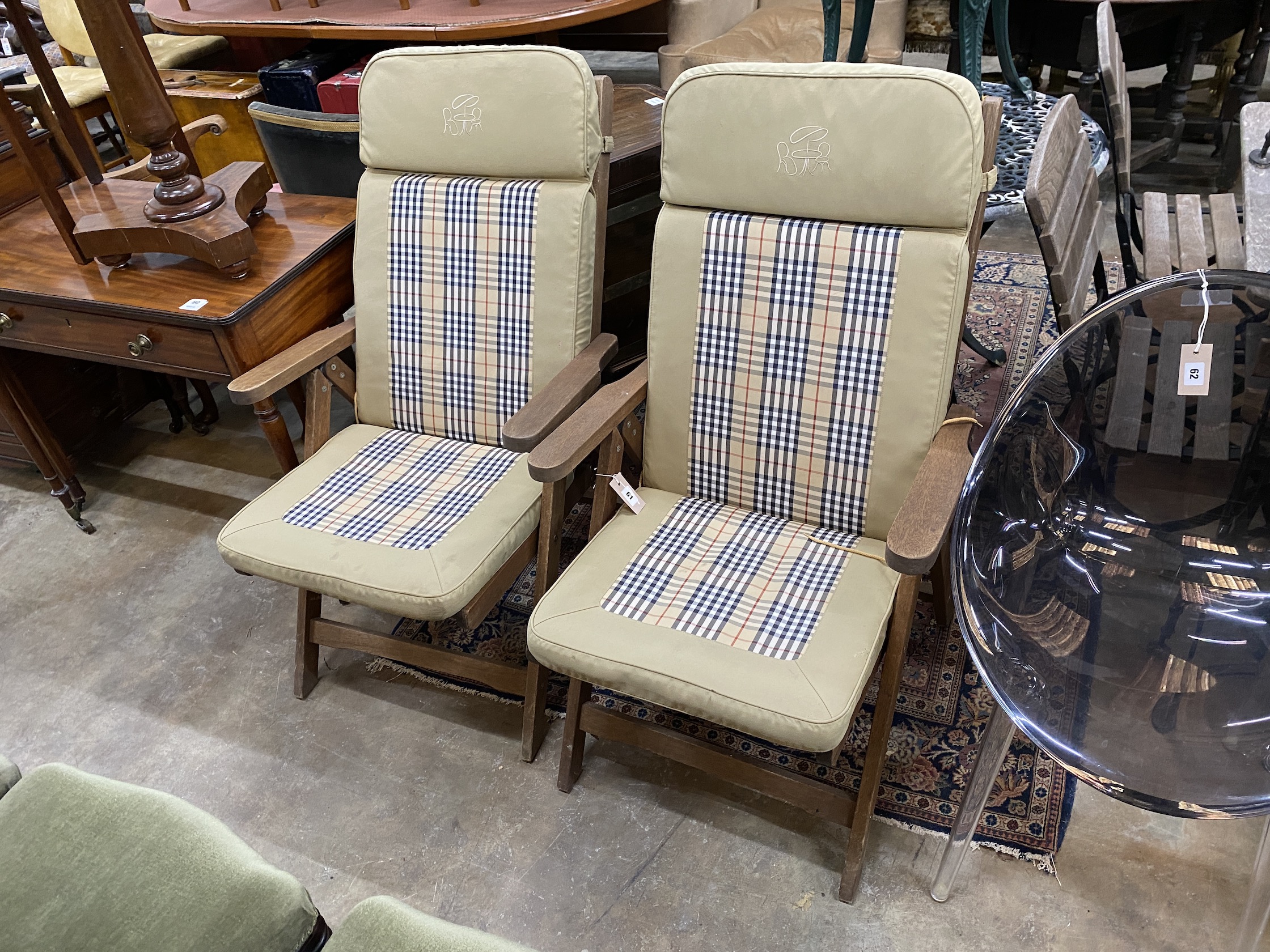 A pair of teak reclining garden elbow chairs with cushions, width 60cm, height 100cm